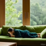 Home 5 소셜미디어에서의 고립감 극복하기 - A young adult in their late 20s, wearing comfortable loungewear, sits on a soft sofa in a warmly lit...
